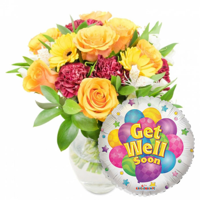 A radiant 'Get Well Soon' arrangement, balanced for optimism and comfort, shown here on a crisp white field. The bouquet occupies the left-to-centre space in a clear glass vase filled with water so the green stems are visible; a glossy round silver Mylar balloon sits lower right, partially overlapping the floral mass. The flowers read as warm and reassuring: large orange and deep yellow roses open in soft spirals, casting a subtle citrus-rose scent, while bright yellow gerbera daisies bring clean, sunny discs of colour. Deep burgundy or maroon carnations introduce plush texture and a grounding tone, and delicate white alstroemeria (Peruvian lilies) thread through the arrangement as small, graceful highlights. Lush green foliage surrounds each bloom, with varied leaf shapes that add movement and a fresh garden quality. The balloon's silvery backdrop frames a playful cluster of cartoon balloons in vivid blues, purples, pinks, greens and yellows, some patterned with stripes or polka dots, and the centre features the friendly script Get Well Soon in yellow and blue with a slight shadow; tiny starburst graphics rim the white border and a KALEIDOSCOPE logo is visible at the very bottom. Lit by soft daylight, the composition conveys gentle encouragement and calm cheer - a thoughtful gift often chosen by neighbours across Epping, from High Street shoppers to families returning from a walk in Epping Forest.