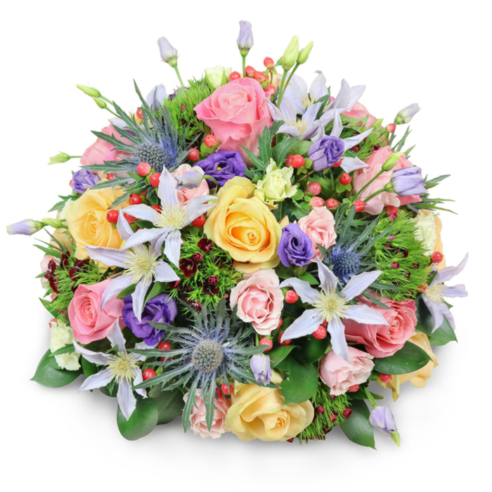 A meticulously arranged, dome-shaped bouquet sits before a stark white background, the composition casting a soft, flattering shadow that highlights its layered depth. The primary visual language is romantic and textural: numerous garden roses in pale pink, creamy peach, and sunny yellow create a voluminous, velvety core, each bloom at a slightly different phase of opening to suggest natural movement. Scattered among them, starry clematis in shades of pale violet and white add delicate points of brightness, their yellow centres offering focused visual anchors. The arrangement's silhouette is given contemporary structure by blue Eryngium (sea holly) thistles-spiky and sculptural with metallic-blue tones-providing a pleasing counterpoint to the roses' softness. Purple lisianthus, some still tightly furled, lend deeper tonal variety while clusters of red Hypericum berries punctuate the palette with glossy, playful pops. A complex bed of greenery supports these elements: wide, lustrous leaves form a foundation; finer, feathery sprigs create breathing room; and darker burgundy filler foliage winks through for contrast and richness. The overall impression is one of thoughtful abundance, smelling faintly of fresh-cut roses and green foliage, evoking a summer morning stroll through Epping Forest or a thoughtful purchase from the High Street florist. This expertly balanced bouquet is equally appropriate as a wedding table centre, a celebratory gift, or a refined sympathy tribute for those receiving blooms in the Epping area.