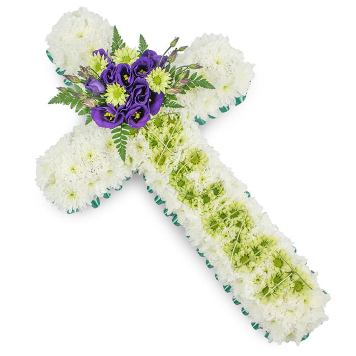 In this image, a meticulously crafted floral cross for a funeral or memorial service is displayed against a plain white background, allowing its colours and textures to stand out clearly. The main structure of the cross is formed from countless small white spray chrysanthemums, packed closely together so that their feathery petals merge into a smooth, cushion-like surface. This blanket of white conveys innocence, peace, and the softness of a final farewell. Encircling the cross from end to end is a narrow but distinct border of bright green ribbon or foliage, outlining the Christian shape with a fresh, contemporary edge that lifts the design without distracting from its solemn purpose. At the centre, where the arms cross, sits a concentrated cluster of accent flowers. There, rich purple Eustoma, or lisianthus, bloom in layered whorls, their deep tones suggesting reverence and spiritual reflection, while bright lime green button chrysanthemums nestle among them, adding lively touches of colour that signal renewal and the promise of new life. Sprigs of deep green fern emerge from behind, splaying gently outward to give depth and a natural, airy feel reminiscent of the green corners and churchyards tucked around Epping High Street. Further down the vertical stem of the cross, a band of lime green chrysanthemums is threaded through the white base, creating a soft central stripe. Fine, pale decorative wires are draped over this section in a subtle criss-cross pattern, adding delicate visual interest on closer inspection. This floral cross, with its harmonious blend of white, green, and purple, makes a dignified and comforting tribute for a Christian funeral, graveside, or remembrance ceremony in and around Epping.