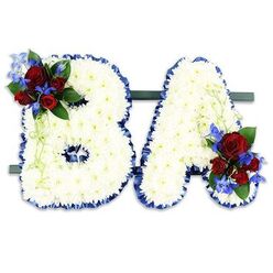 Expertly crafted by a local hand, this pair of freestanding floral initials presents the letters "B" and "A" as a single unified memorial. Each letter is formed from a dense sea of small, immaculate white chrysanthemums whose layered petals create a soft, tactile surface that soothes the eye. The edges are framed with a ruffled royal-blue satin ribbon that provides a striking contrast, sharpening each curve and angle while lending a touch of refined dignity. At the upper left loop of the 'B' sits a lush spray of deep red roses, their velvety faces moving from tight buds to half-open blooms, threaded through with vivid, spiky blue delphinium stems and woven with darker and lighter green foliage. The 'A' receives a matching cluster at its lower right, mirroring the tones and texture to create a balanced, heartfelt composition. The initials are mounted on a slender dark-green base, making them easy to position on a church altar or beside a memorial plaque. Intended for moments of farewell, this arrangement carries the quiet scents of roses and the clean green note of chrysanthemums. Designed in Epping with sensitivity to local services around the High Street, St John's and the lanes that lead into Epping Forest, this piece is available through Flowers Epping for families seeking a personalised tribute that speaks gently of love, honour and remembrance.