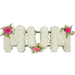 A tender funeral flower arrangement forms the word "MUM" in striking capital block letters, set against a bright, uncluttered white background that lets the details shine. Each letter is densely packed with countless small white chrysanthemum heads, laid so close together they create a velvety, cloud-like surface, symbolising innocence, peace, and the quiet strength of a mother's love. Along the underside of the letters, a dark green ribbon edge and the discreet support frame peek through, lending both stability and a gentle outline that makes the shapes easy to read, even from a distance in a church or crematorium chapel around Epping. Colour is introduced with three carefully placed accent clusters. On the upper left of the first "M," a bright fuchsia garden rose unfurls among paler pink spray roses and delicate fern fronds, the petals full and softly curled. Another cluster rests in the lower central dip of the "U," its roses and buds cradled within the white blooms, like a small, beating heart in the middle of the tribute. The final grouping crowns the upper right of the second "M," mirroring the first and bringing a graceful sense of symmetry. The interplay of crisp white and vivid pink, along with the feathery green foliage, gives the design a gentle movement, as though a breeze is passing through a garden near Epping High Street. This floral lettering feels deeply personal, the kind of bespoke memorial a family might choose to say thank you and goodbye to their mum, offering a message of love, remembrance, and respect crafted entirely in fresh, fragrant flowers.