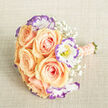 From a slightly raised viewpoint the bouquet lies against a light beige, linen-like surface, its textures and tonal subtleties clearly visible in soft natural light. At the centre, six to eight apricot-peach roses bloom with structured, spiralled layers of petal - plush, warm, and inviting - their colour moving from gentle peach toward a kiss of pink at the petal edges. Interspersed are frilled white lisianthus blooms whose petals are artistically rimmed in violet-purple, the thin amethyst outlines lending a cool, contemporary counterpoint to the roses' warmth; tiny yellow stamens in their hearts add a precise bright note. Sprigs of delicate baby's breath float through the arrangement, providing an ethereal filigree that softens and balances the composition without stealing focus. The handle is carefully wrapped in a coordinating peach ribbon and trimmed with rows of small cream pearls, a refined tactile accent you can imagine slipping into the palm during a ceremony. Neatly cut green stems peek from the base, clean and fresh. The lighting is even and flattering, revealing petal textures and the bouquet's restrained sophistication. This piece reads as a romantic bridal bouquet or an elevated centrepiece - ideal for a ceremony near Epping Market or a reception after a stroll through Epping Forest - and conveys the quiet elegance and thoughtful craftsmanship a local florist would choose for meaningful moments and celebrations.