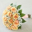 This exquisite hand-tied bouquet, styled in Epping with true local artistry, expresses gentle sophistication and a sense of anticipation perfect for any cherished life event. At its heart are sumptuous peach and apricot roses, each flower opening in soft, spiraled layers-a living slow-dance of colour transitioning from creamy peach to golden apricot, reminiscent of tranquil early mornings in Epping's countryside. Wisps of immaculate white gypsophila envelop the blooms like a bridal veil, imparting an airy, almost ethereal grace. Deep green leaves, glossy and abundant, fan outward, accentuating the roses' radiant tones and grounding the bouquet with refreshing vibrancy. The stems are snugly wrapped with a sumptuous peach satin ribbon, meticulously adorned with a pattern of dainty white pearls, giving a tactile nod to classic wedding elegance often found in Epping's registry offices and local celebrations. Presented diagonally atop a pale, finely textured cloth, every nuance of colour and shape is celebrated by the glow of natural light. The scent-delicate, sweet, and fresh-evokes the feeling of a walk in Epping Forest during spring. Thoughtfully crafted, this bouquet captures both tradition and contemporary grace, destined to mark unforgettable moments for couples or families across Epping, where memories are cherished and every celebration is treated with the utmost care.