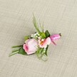 Softly illuminated by gentle daylight, a refined pink rose boutonniere lies thoughtfully arranged on a pale beige linen background, echoing the calm elegance of Epping's countryside weddings. At its heart, the fresh rose's tightly coiled petals deepen from pastel pink to a richer tone at the centre, reflecting an artistry familiar to Epping's finest local florists. A paler peach or pink flower, perhaps an artful Alstroemeria, blooms nearby, its subtle yellow throat and fine markings drawing the eye and adding layers of grace. Tiny clusters of baby's breath add a touch of lightness, while minute green chrysanthemum spheres create lively definition. Lush leaves in varying shades-slender blades and broader, glossy greens-offer structure and vibrancy, their arrangement recalling walks through Epping Forest's leafy trails. One wide, deep green leaf is elegantly wrapped around the base, gathering the stems together. The boutique arrangement is finished with a striking fuchsia satin ribbon, its glossy bow symbolising festivity and sentimental warmth. Resting upon textured linen evocative of Epping's traditional interiors, this boutonniere is destined for those cherished milestones-a wedding at Copped Hall, a prom night, or an anniversary celebrated with loved ones. The careful blend of blush petals, lush greenery, and festive ribbon embodies romance and modern elegance, a floral creation as thoughtfully designed as any moment along Epping's green lanes.