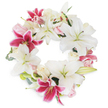 Against a backdrop as white as morning frost on Epping's High Street, a sumptuous funeral wreath unfolds-a timeless arrangement crafted with care by local hands. The wreath forms a complete, elegant ring, the outer edges lined with large, trumpet-shaped white lilies whose silky petals and pale stamens evoke peace and fresh beginnings. Throughout, fuchsia-pink lilies add vivid splashes of colour, their star-shaped forms and speckled interiors providing movement and visual interest among the restful whites. Blush roses in soft pink and creamy hues are gathered in between the lilies, their tightly layered petals hinting at gentleness and hope, while small sprays of muted green foliage impart an organic freshness-a subtle nod to the ancient greenery of nearby Epping Forest. Every element is artfully arranged to embody dignity, comfort, and continuous life, making it a meaningful tribute for memorials or funerals around the Epping community. This lush and harmonious circle, blending vibrant lilies and tender roses, offers not only a visual tribute, but a heartfelt message of remembrance and sympathy from a trusted Epping florist who understands the emotional resonance flowers can bring.